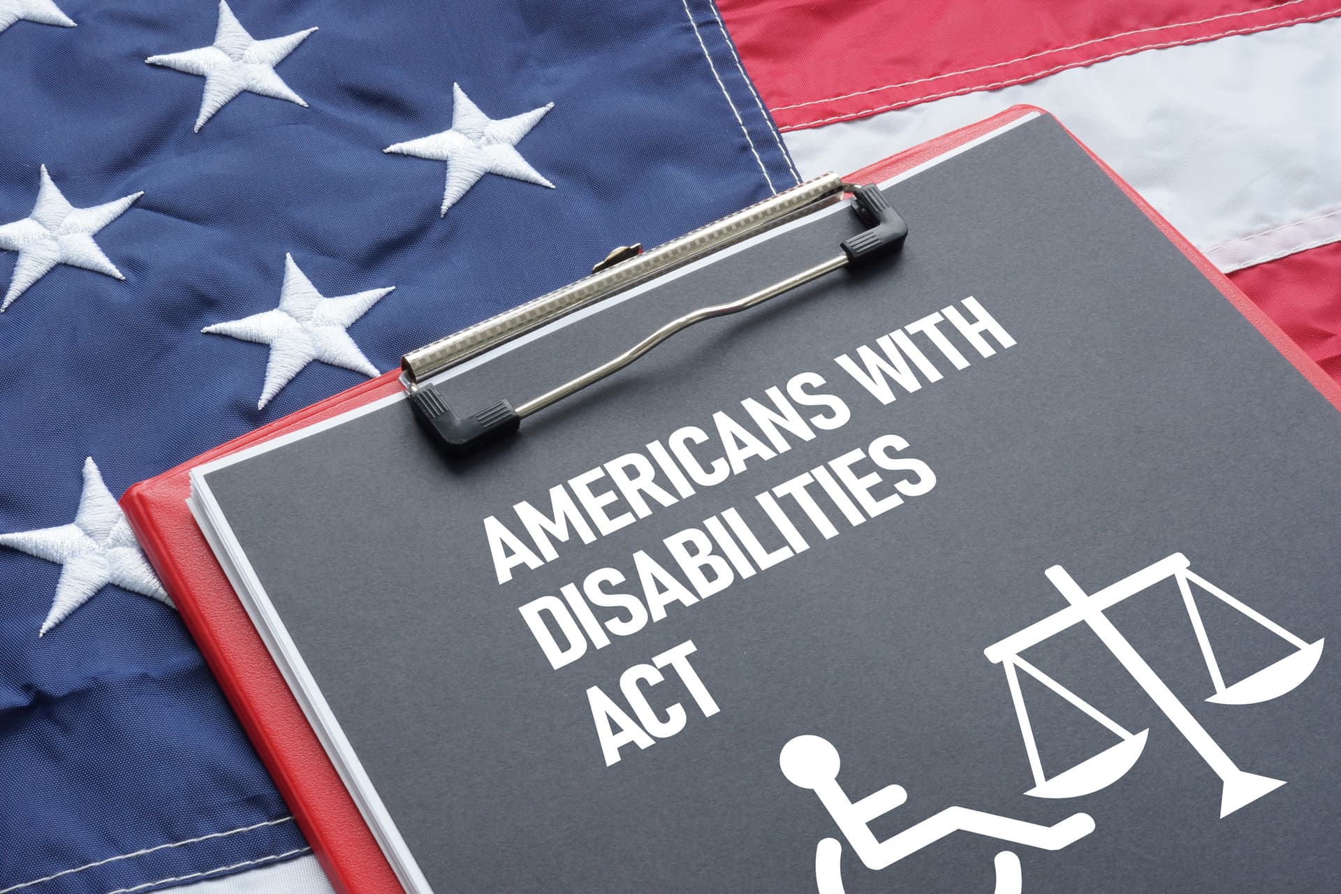 A sign that reads Americans with disabilities act with the American flag in the background