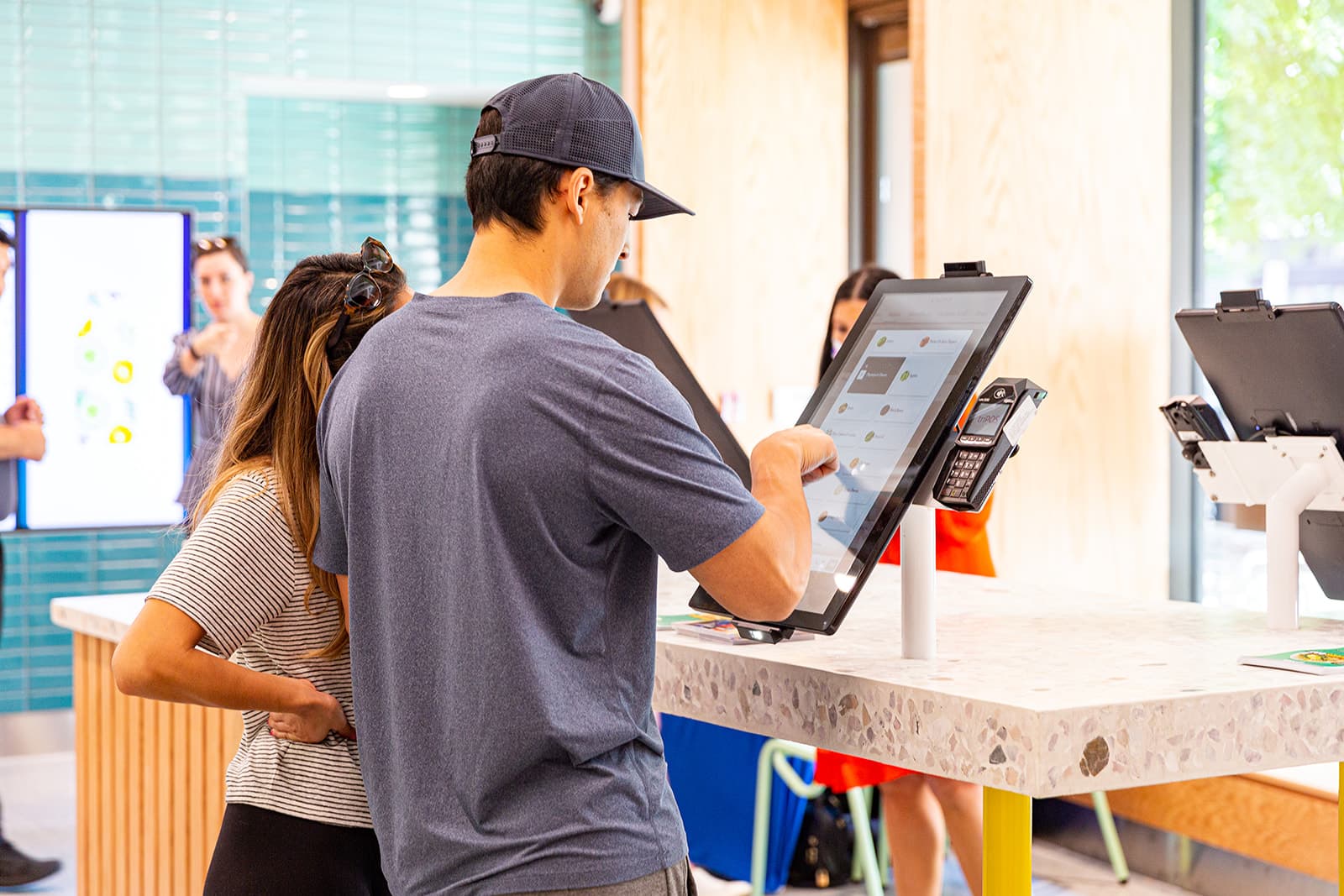 A man and a woman using a restaurant kiosk from Bite