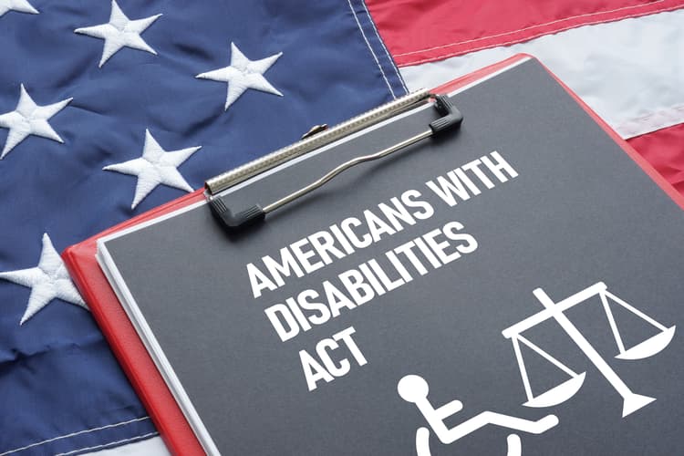 A sign that reads Americans with disabilities act with the American flag in the background