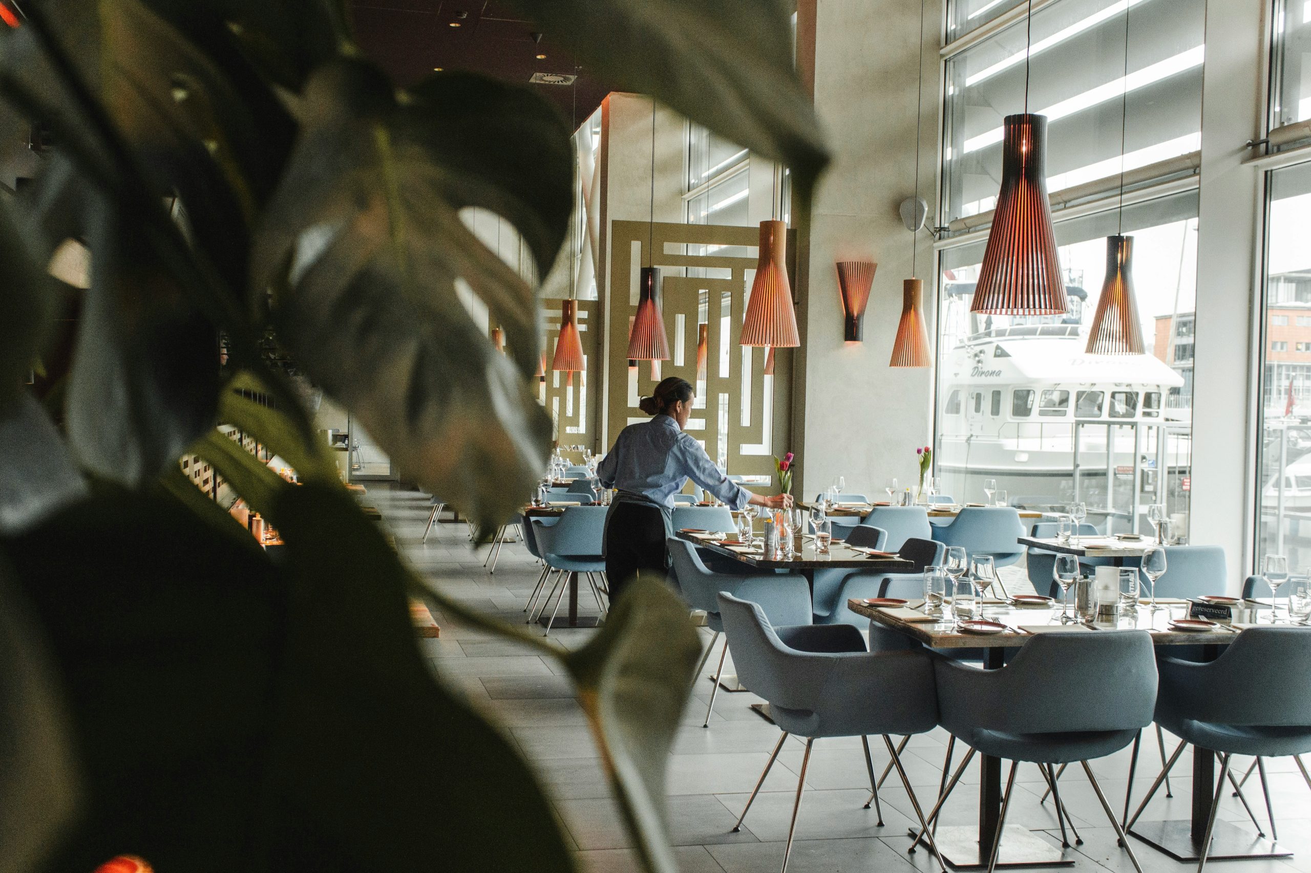 A woman working at a restaurant setting a table