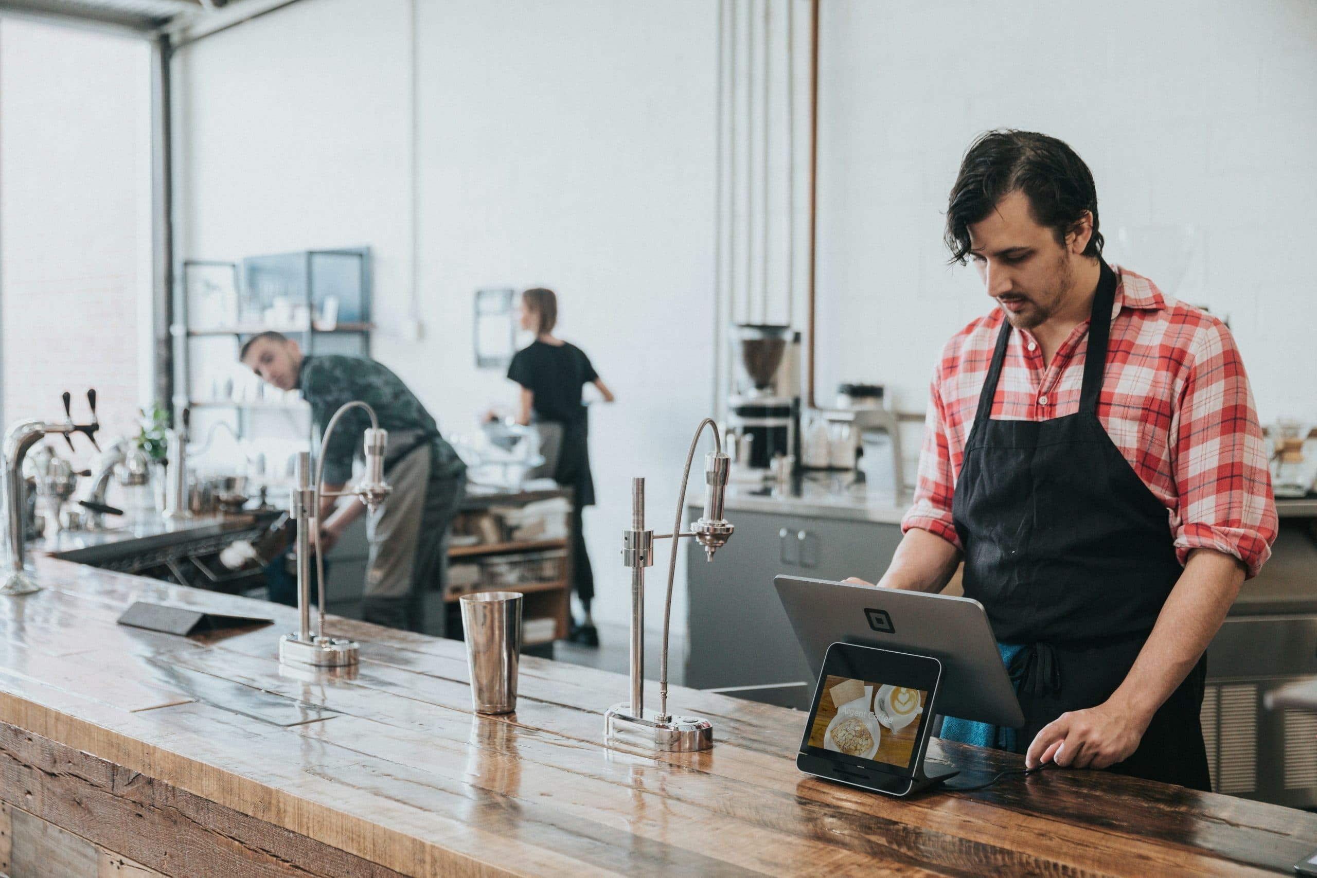A worker at a cafe looking at a POS