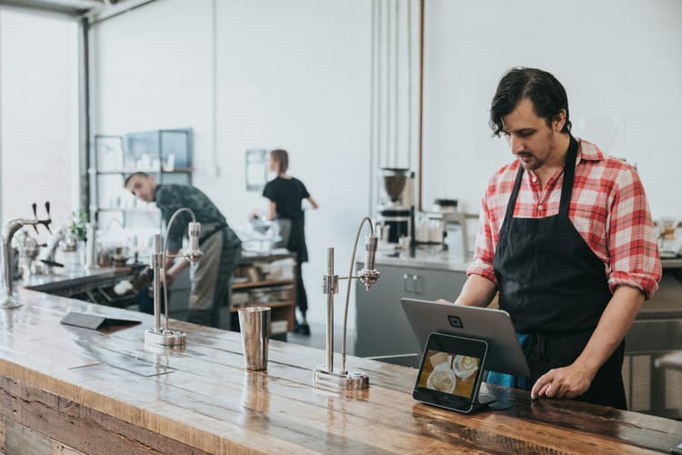 A worker at a cafe looking at a POS